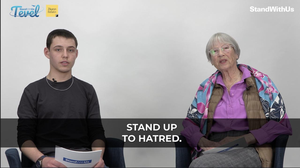 Two people sit side by side in a studio; a young man on the left and an older woman on the right, with a banner reading 'STAND UP TO HATE' across the foreground and StandWithUs logos overhead.